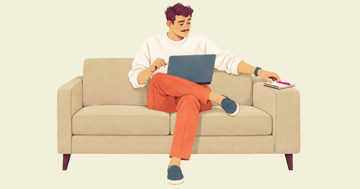 Ivo on a sofa with his laptop on his knees, one hand hovering over it, reaches for a notebook and pink pen on the armrest instead.