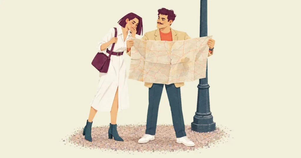 Ivo proudly holding open a huge, worn paper road map beside a lamppost on a gravel patch while Mira leans in from the side to look at it, a hand over her mouth to hide a laugh.
